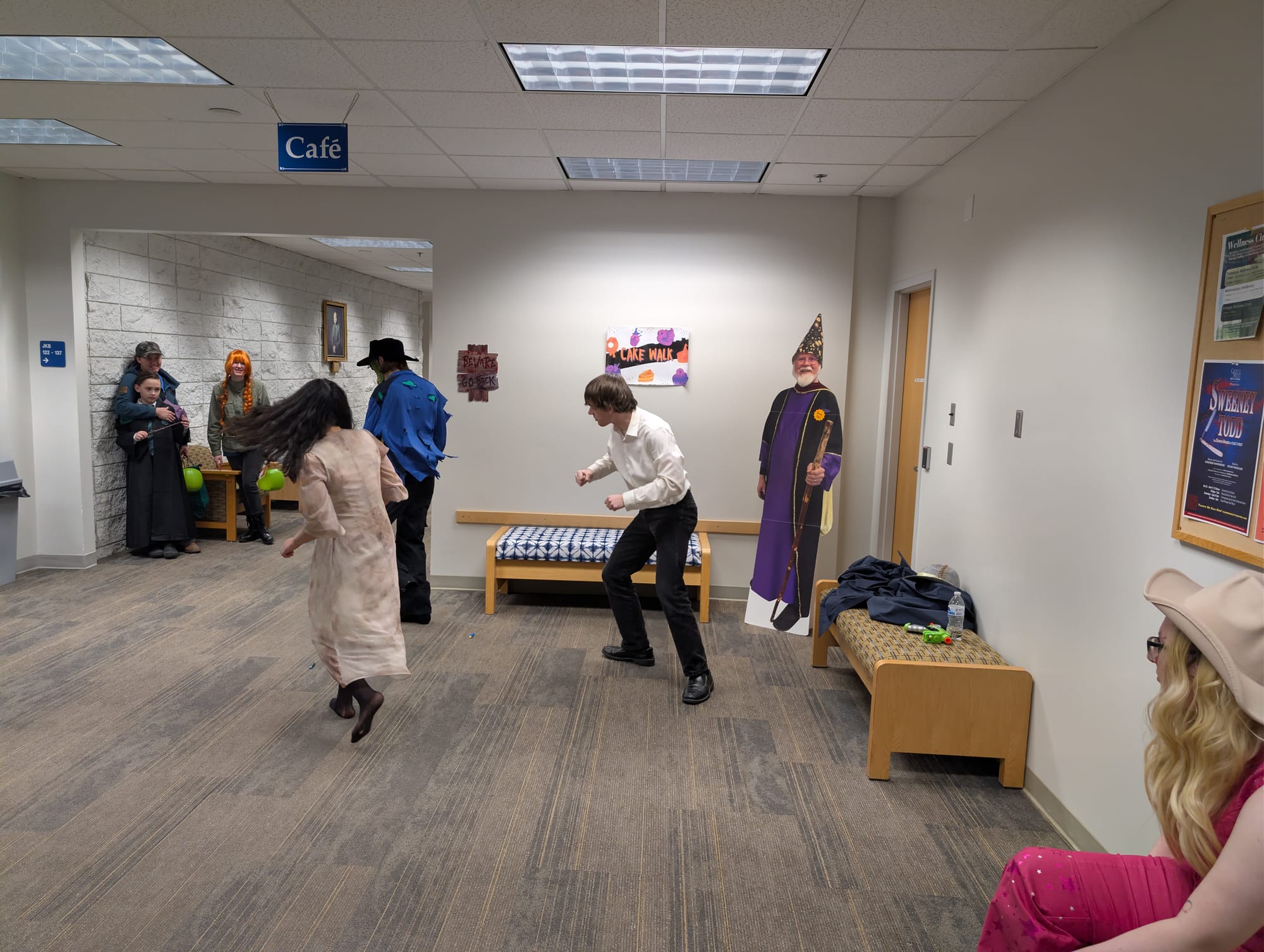 Three students, two in costume, dance in front of a small audience.