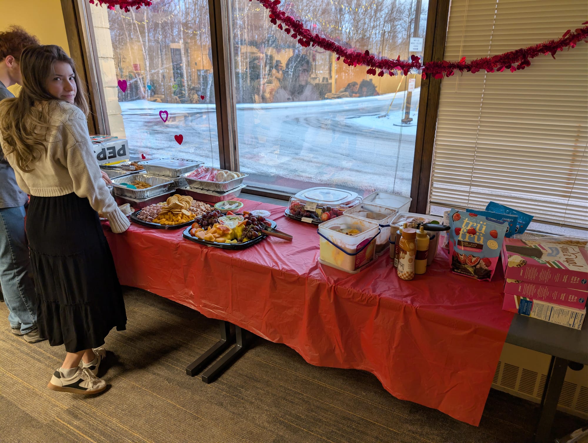 Two students look at a table full of food.