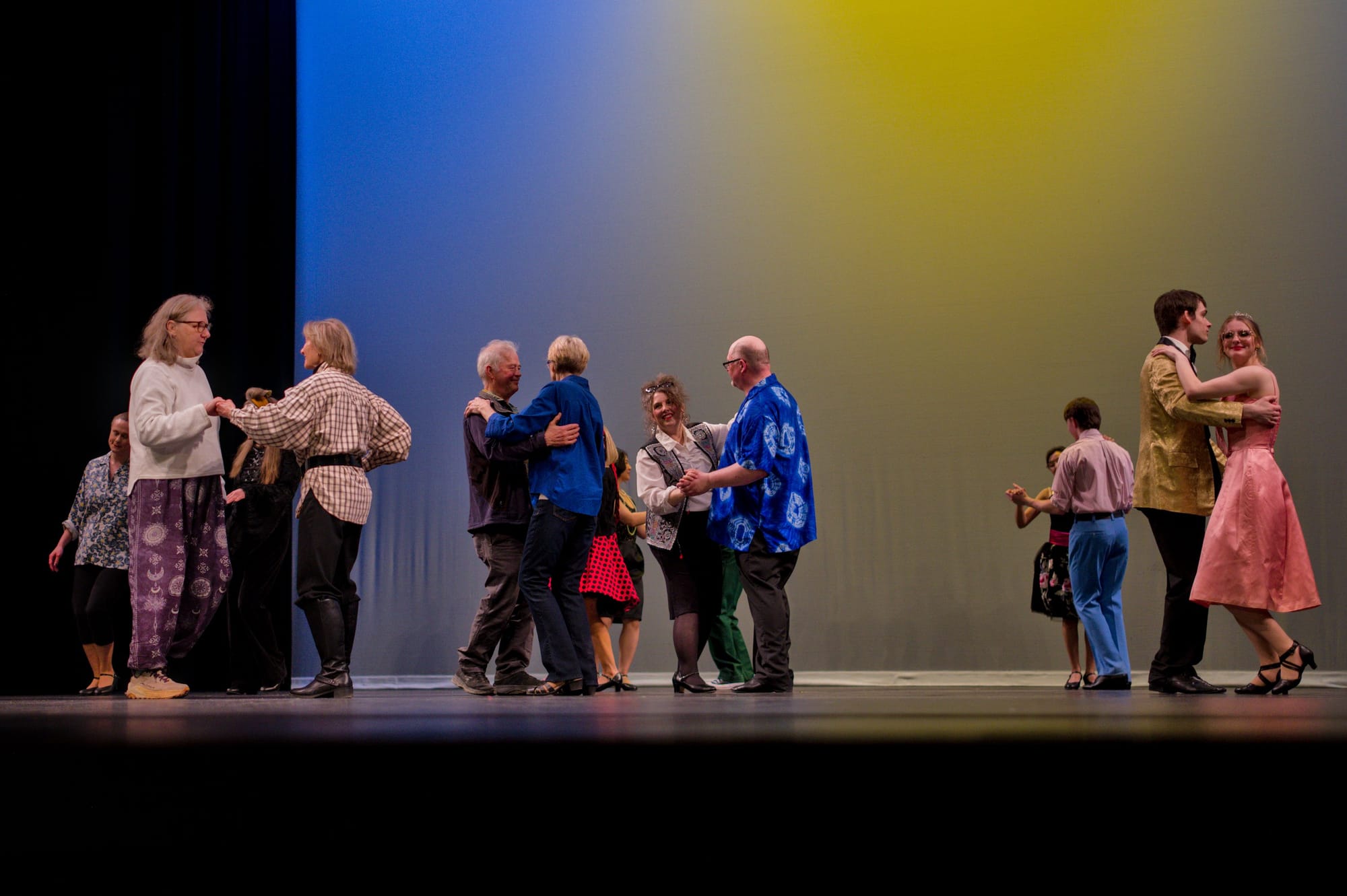 About 10 people of all ages dancing on the stage in pairs.