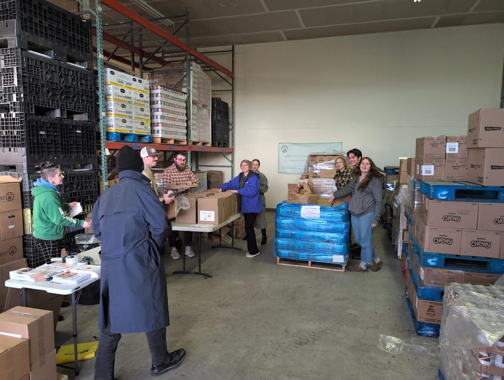 A warehouse scene with students and staff filling cardboard boxes.