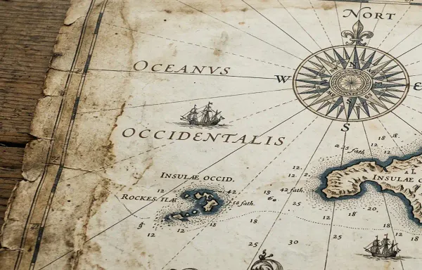 A close-up of an antique nautical chart on aged parchment showing hand-drawn coastlines and a compass rose, in muted sepia and blue-grey tones. No modern text is visible.
