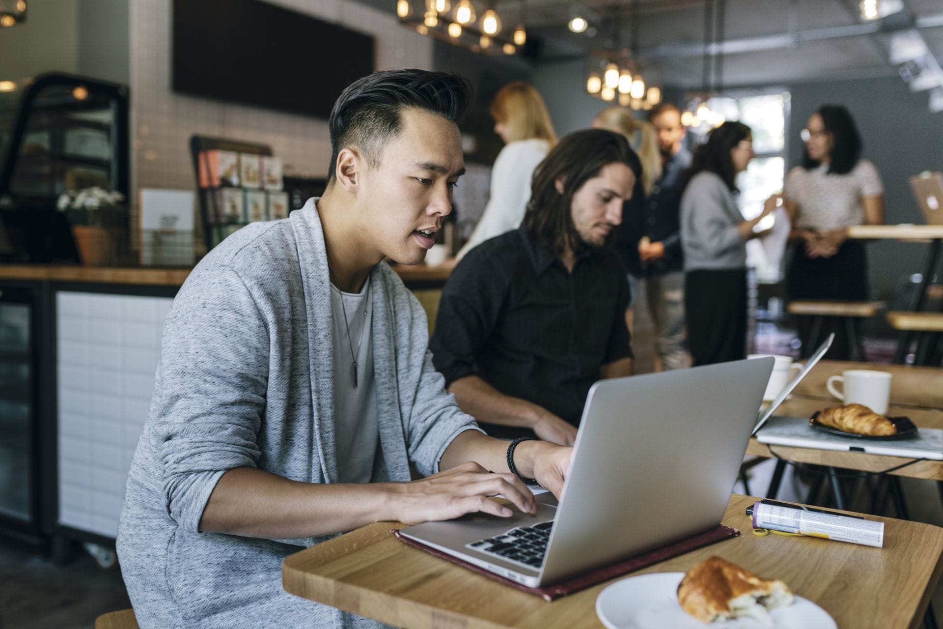 A cafe in which a couple of people are sitting at tables while working on their laptops