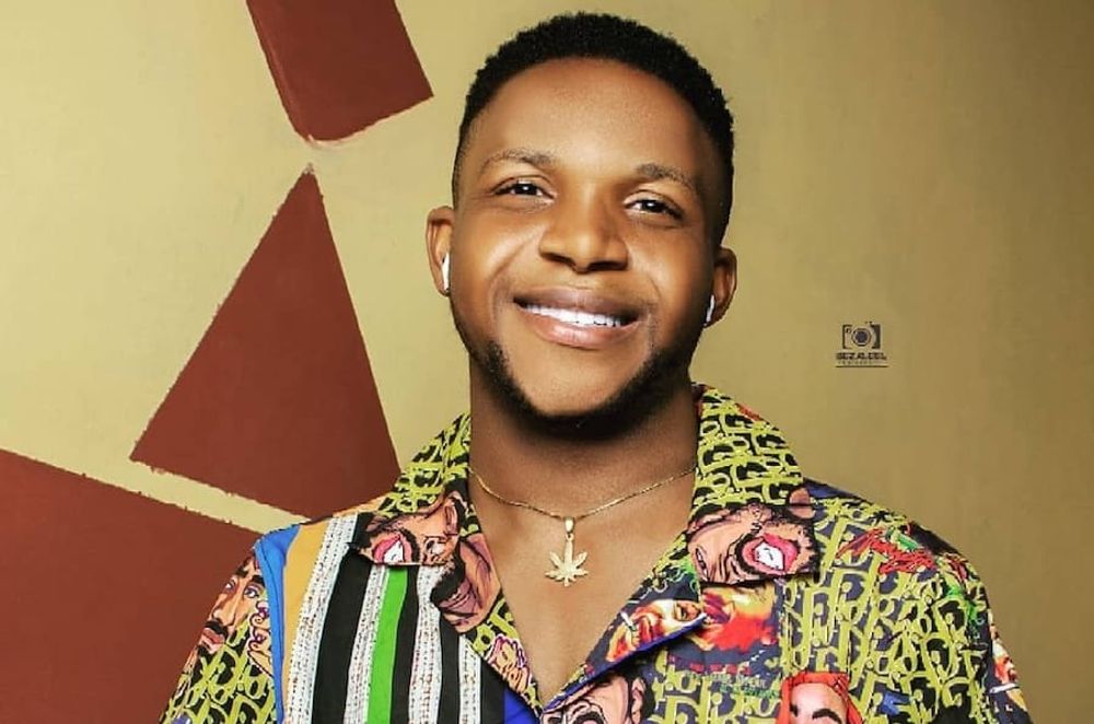 Samuel, a blxck boy by heritage and not complexion, sits on the only chair in his study room, wearing a smirk, multi-colered T-shirt, a wrist watch & a neck chain.