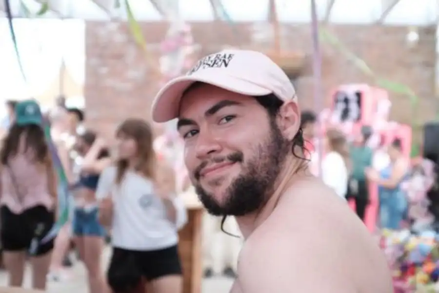 The author in a baseball cap looks back at the camera and smiles in front of a crowd of dancing people.