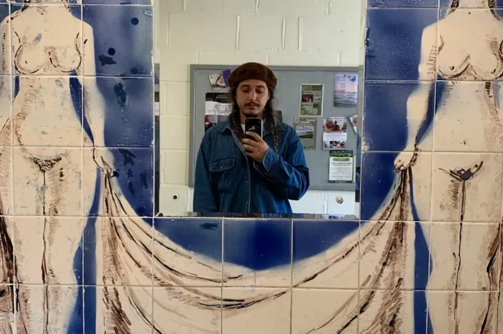 Selfie taken in a bathroom mirror framed with ornately painted tiles.