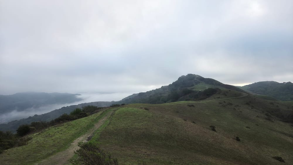 Trail disappearing over ridgeline fog blanketing valley beyond