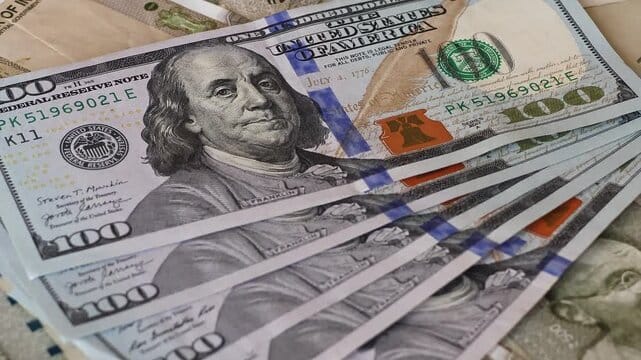 Close-up of stacked US one-hundred-dollar bills showing Benjamin Franklin portraits.