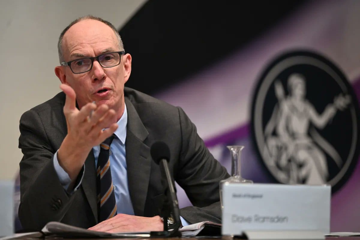 Man in glasses and dark suit speaking at a table with microphone and Dave Ramsden nameplate, Bank of England logo behind.