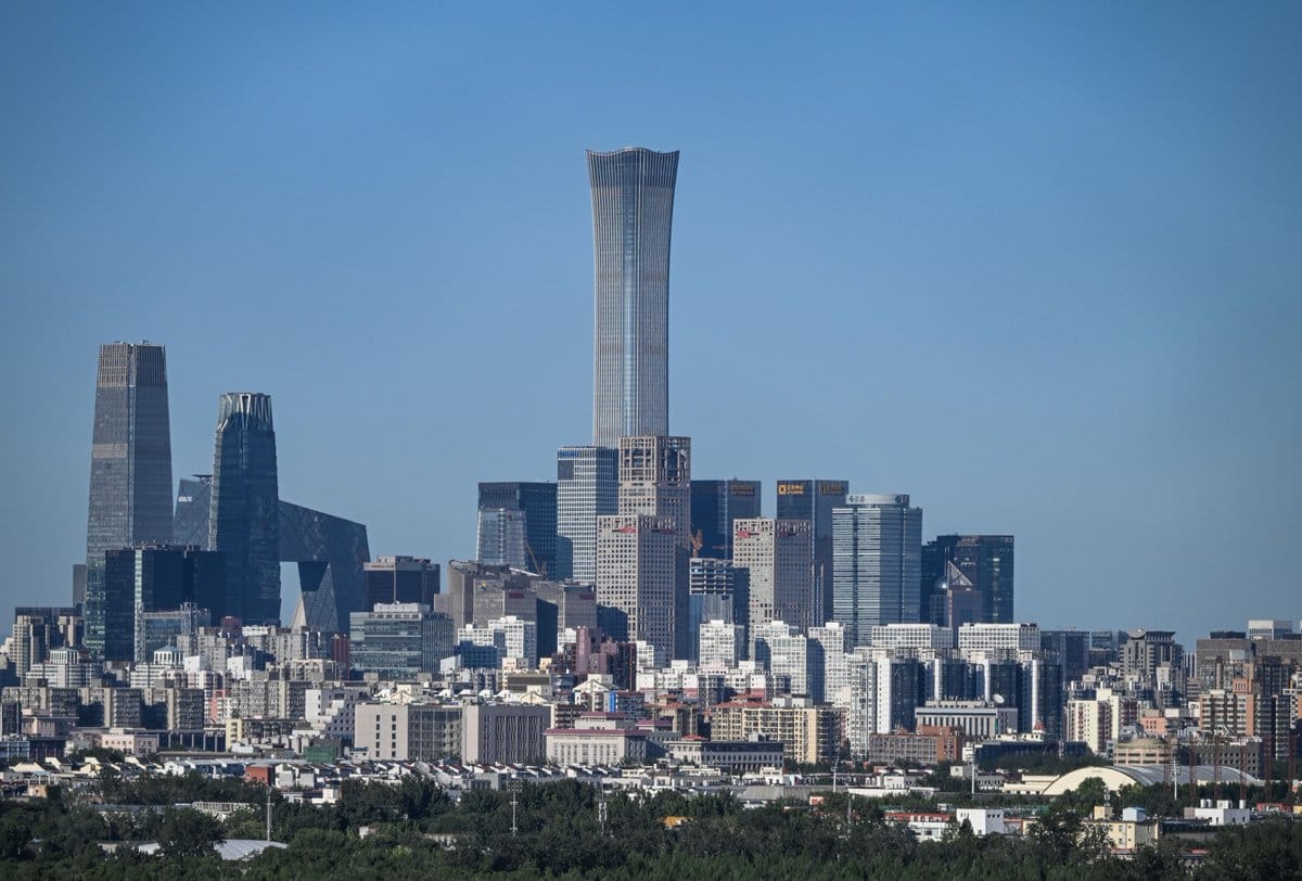 Beijing CBD skyline with China Zun and CCTV Headquarters under a clear blue sky, mid-rise buildings and trees in the foreground.