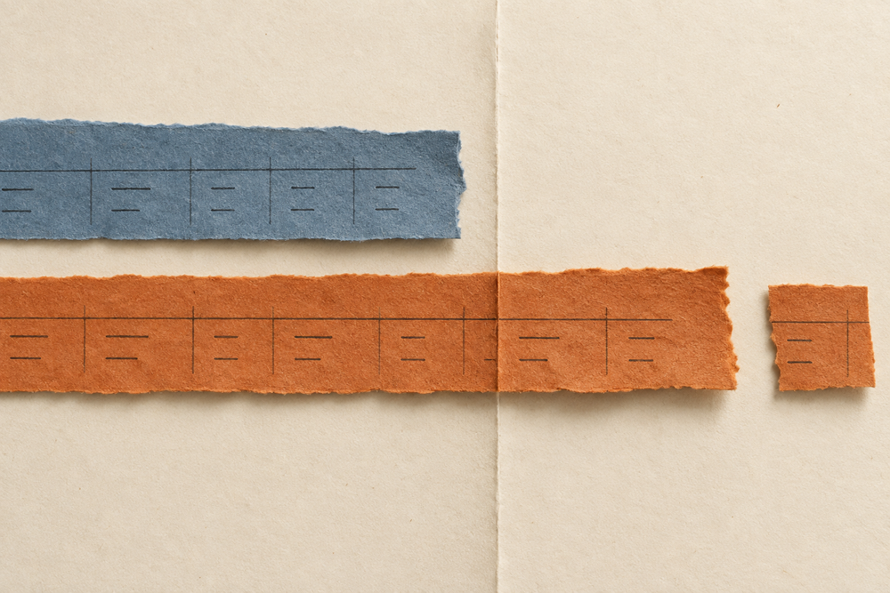 Blue and orange strips of ruled paper stop at different points around a fold, with a small orange fragment on the far side.